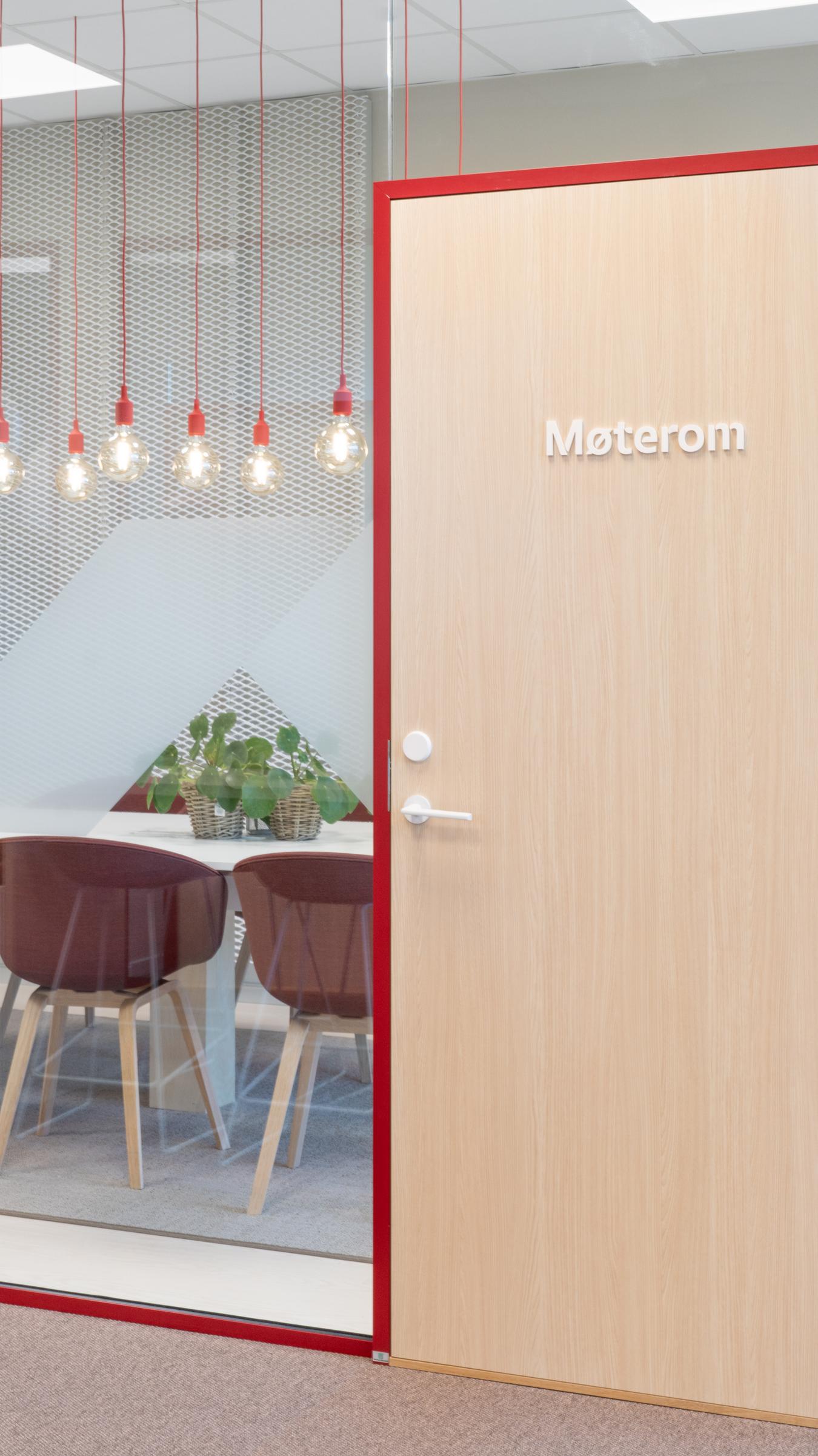 Innglassert møterom med røde detaljer i interiør. Foto