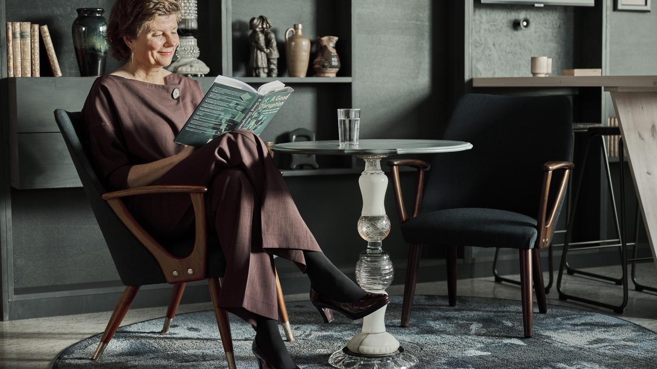 Kvinne i lenestol som leser en bok. Foto