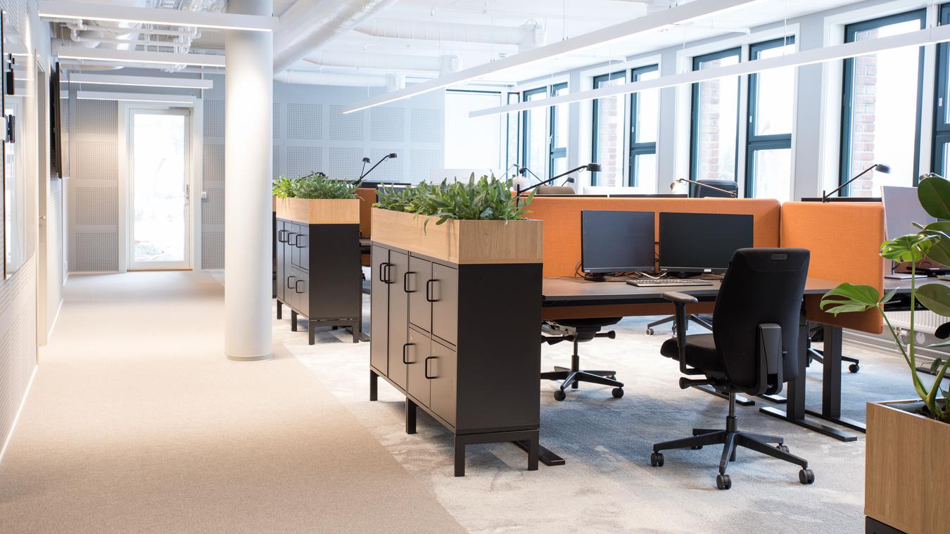 Kontorlandskap med detaljer i sorte og oransje farger og lun stemning med planter. Foto