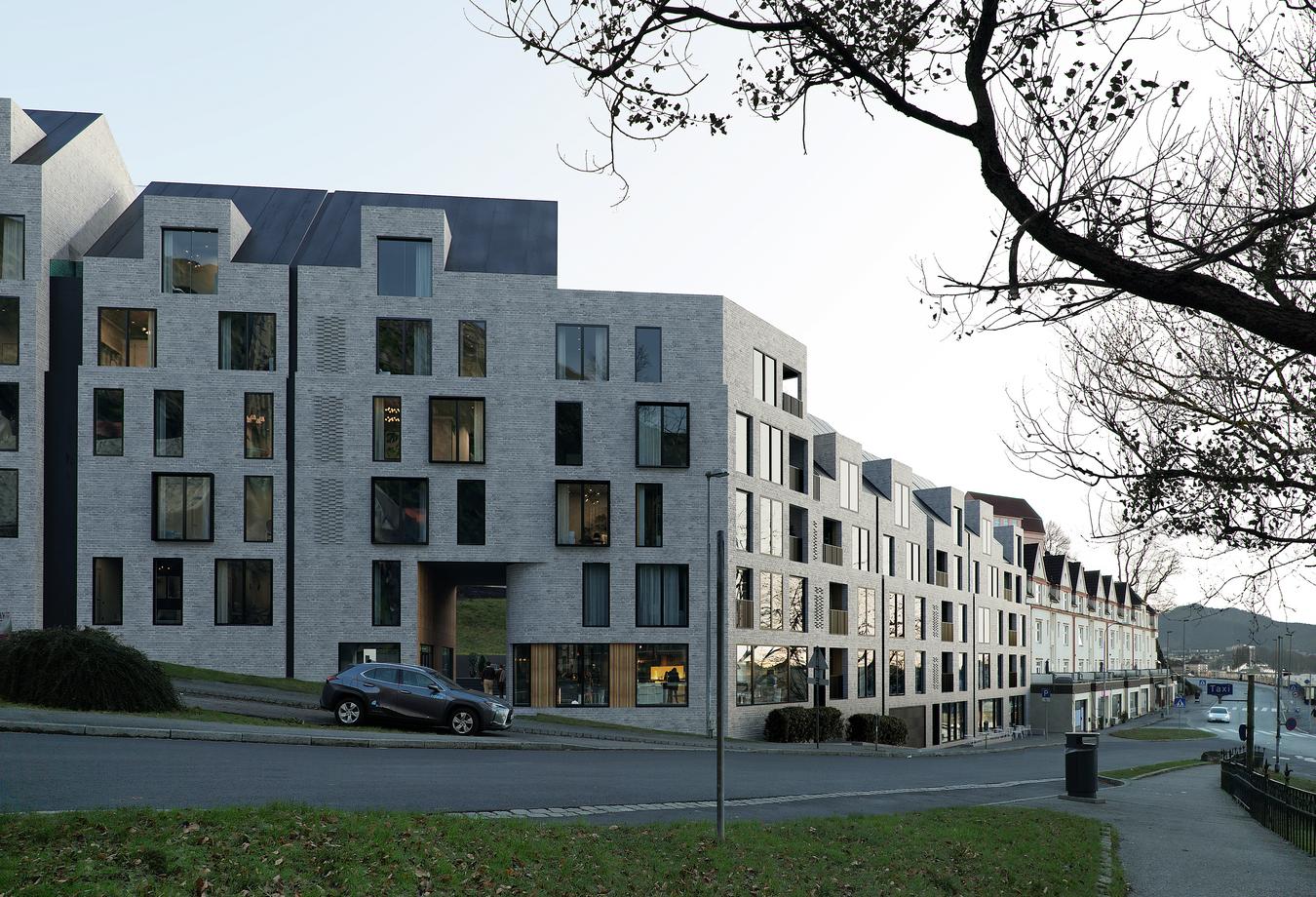 Grå mursteinsfasade med firkantede vinduer på boligbygg. Illustrasjon