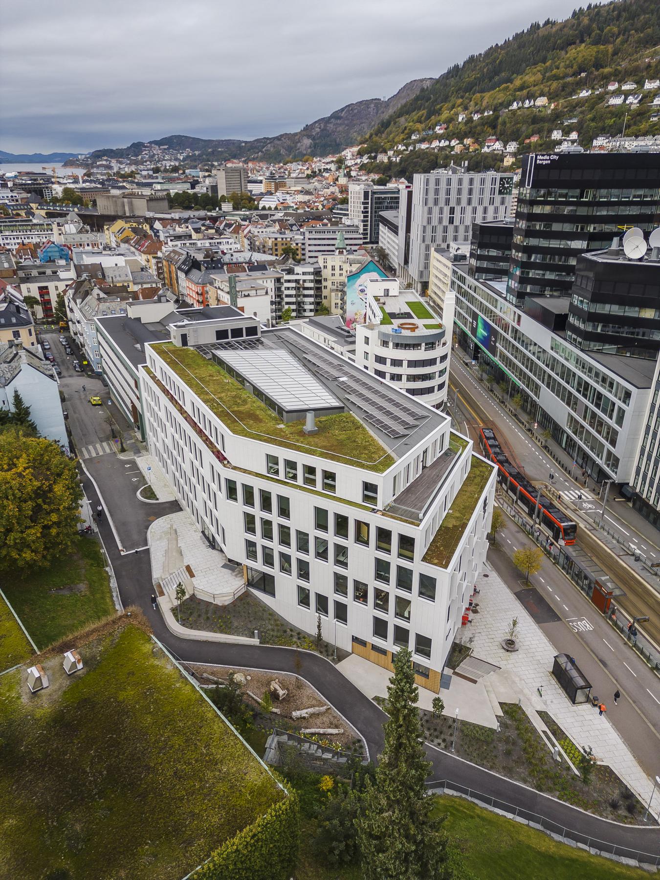 Dronebilde av hvitt kontorbygg i bymiljø. Foto