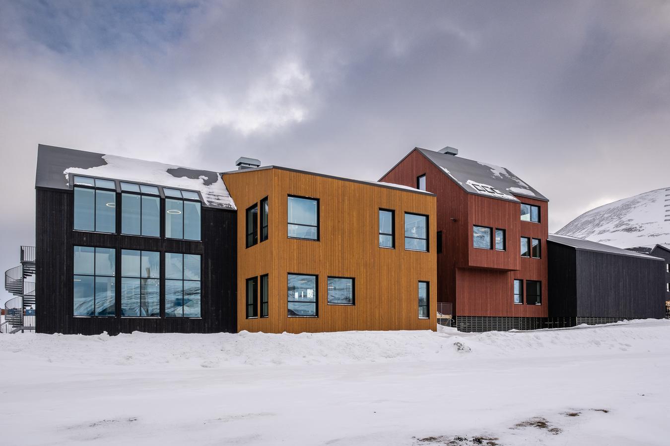 Tre hektede bygg i tre. Fasade i sort, sennepsgul og rustrød. Foto
