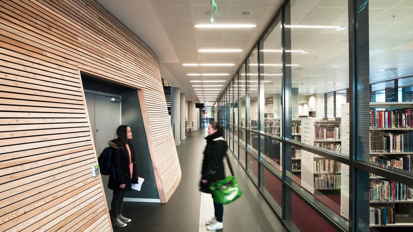 Entre med trævæg og glasfacade og to elever. Foto